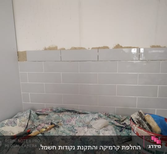 כלי עבודה ודלי צבע על רקע קיר עם אריחים